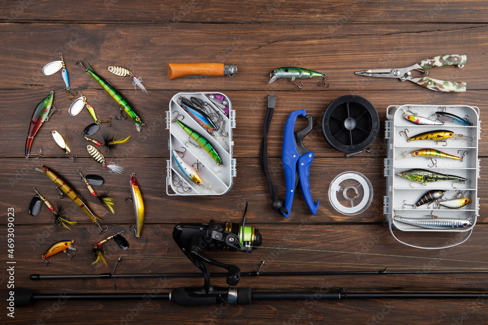 Fishing tackle - fishing spinning rod, hooks and lures on wooden background. Active hobby recreation