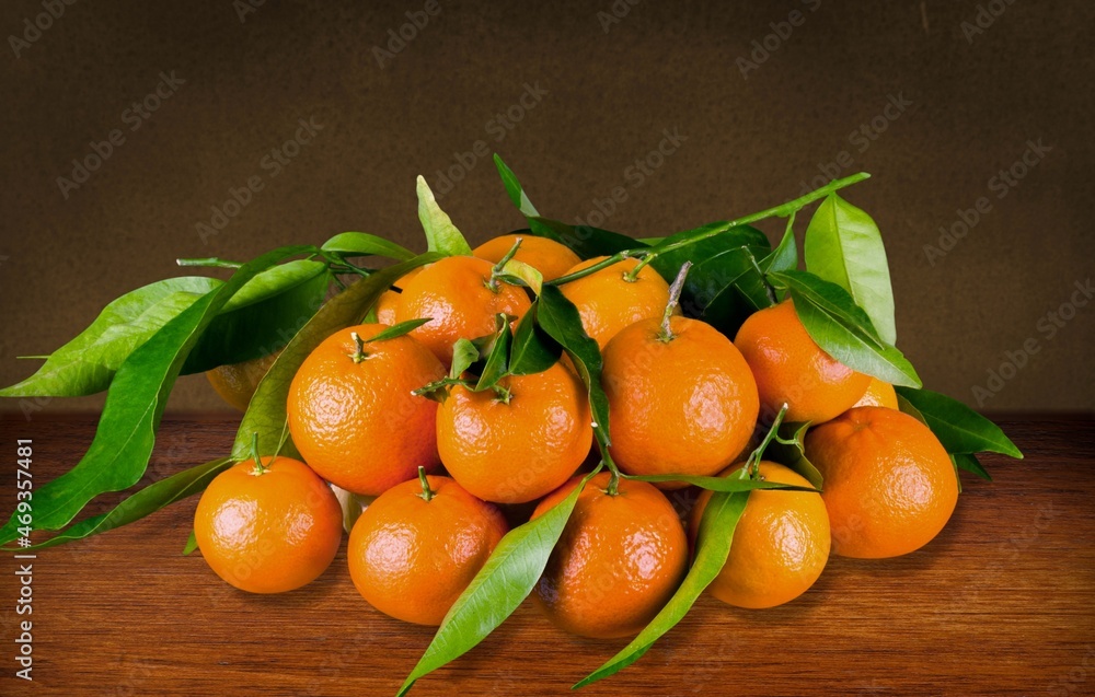 Fresh mandarin oranges fruit or tangerines with leaves on a desk