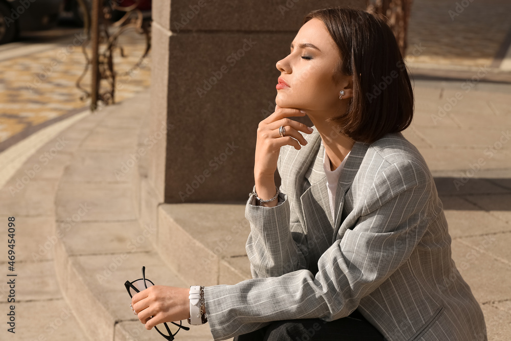 Beautiful woman with closed eyes enjoying sunny day on city street