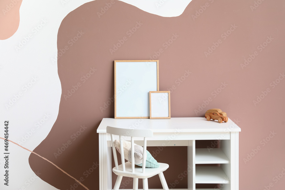 Table with wooden cars and blank frames near color wall