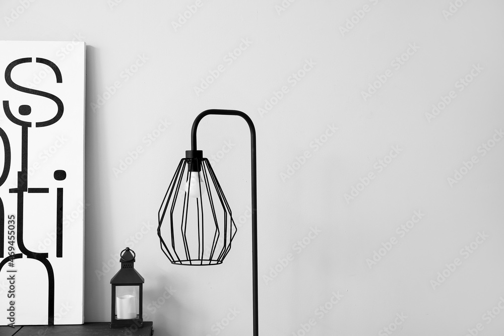 Stylish black lamp on wall background