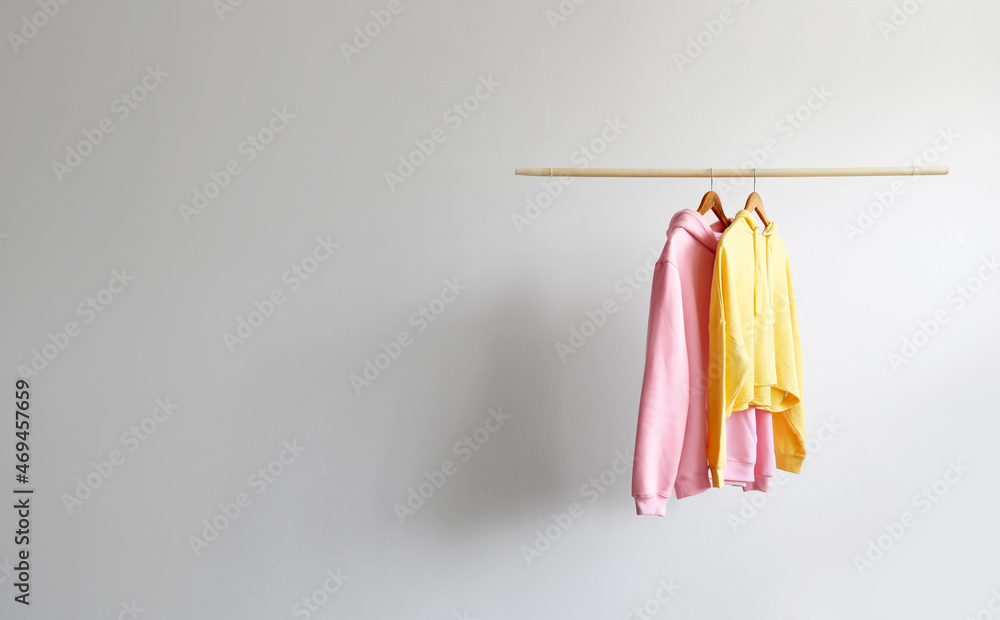 Modern hoodies hanging on light wall