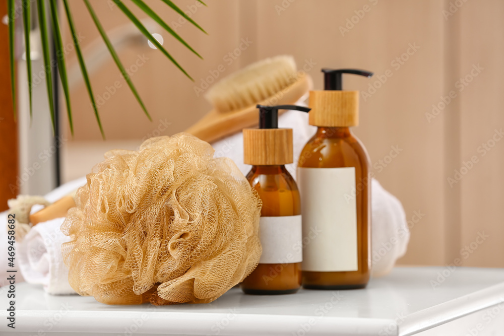 Bath sponge and bottles of cosmetic products on table