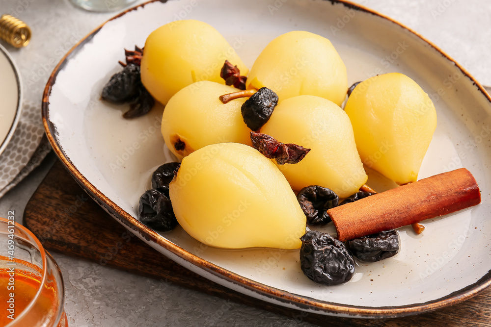 Dish with poached pears, prunes, anise and cinnamon on light table, closeup