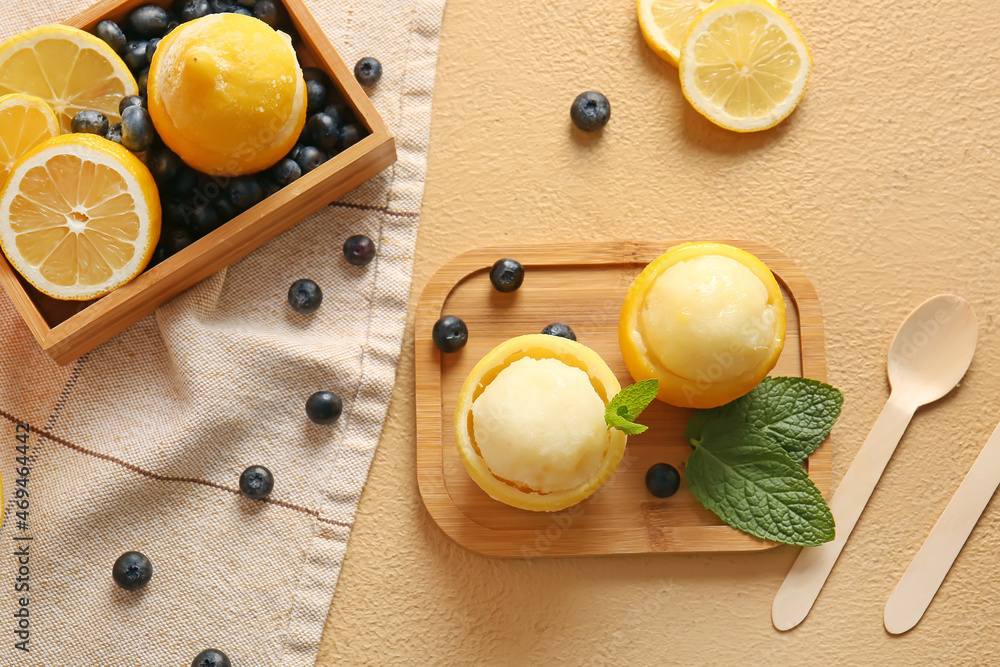 Board with tasty ice creams in lemon peels on color background