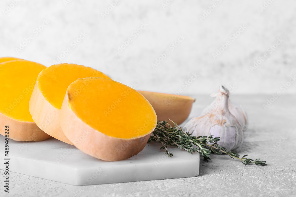 Board with fresh pumpkin pieces on light background