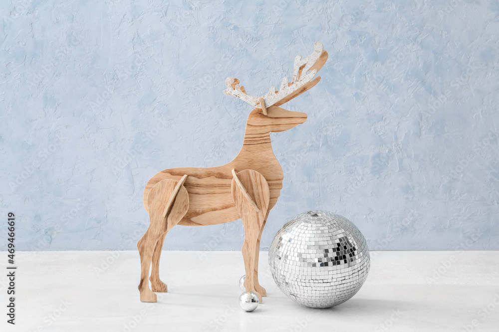 Wooden reindeer, Christmas balls and disco ball on color background