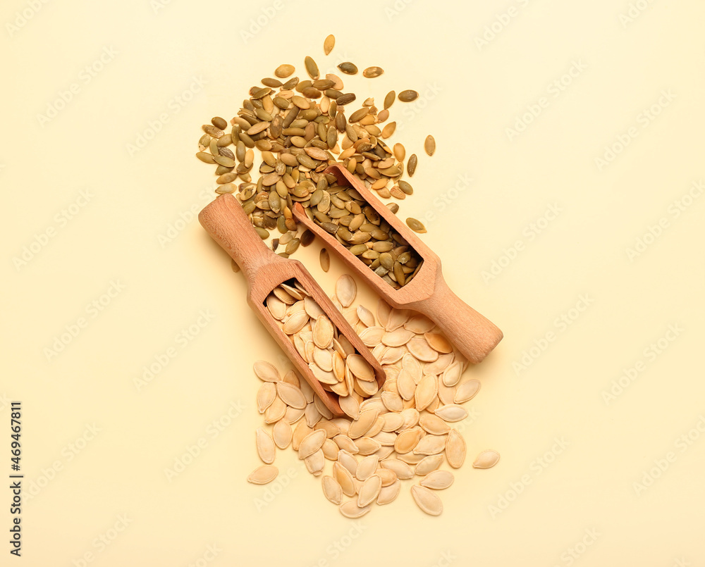 Scoops with natural pumpkin seeds on yellow background