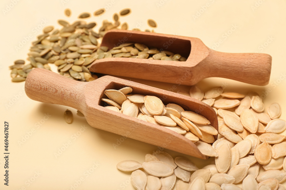 Scoops with natural pumpkin seeds on yellow background