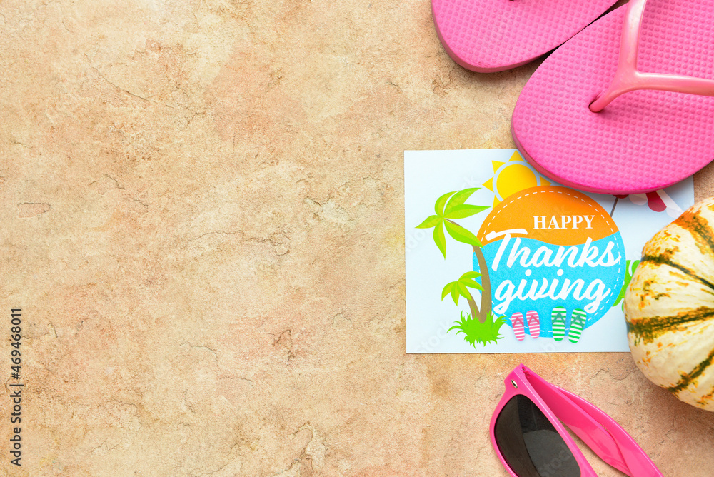 Flip flops, pumpkin, sunglasses and paper card with text HAPPY THANKSGIVING on color background