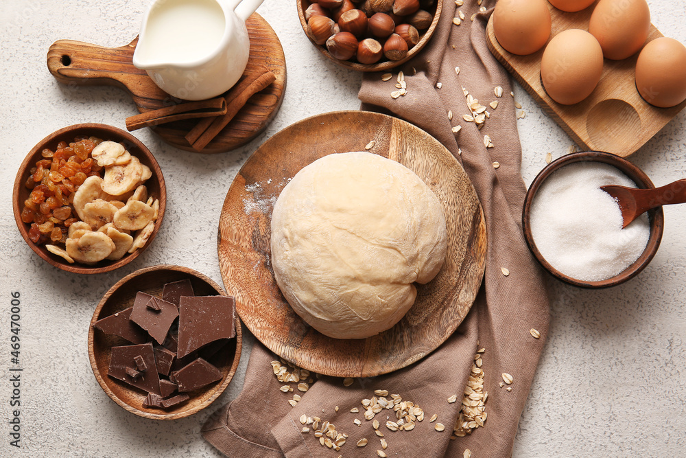 Plate with fresh dough and ingredients for preparing homemade cookies on light background