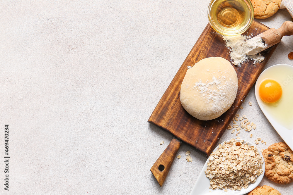 Wooden board with dough for preparing homemade cookies and ingredients on light background