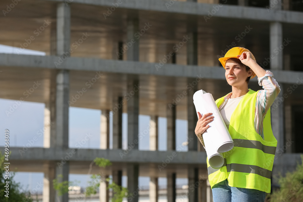 戴安全帽的女建筑工人在户外拿着纸卷