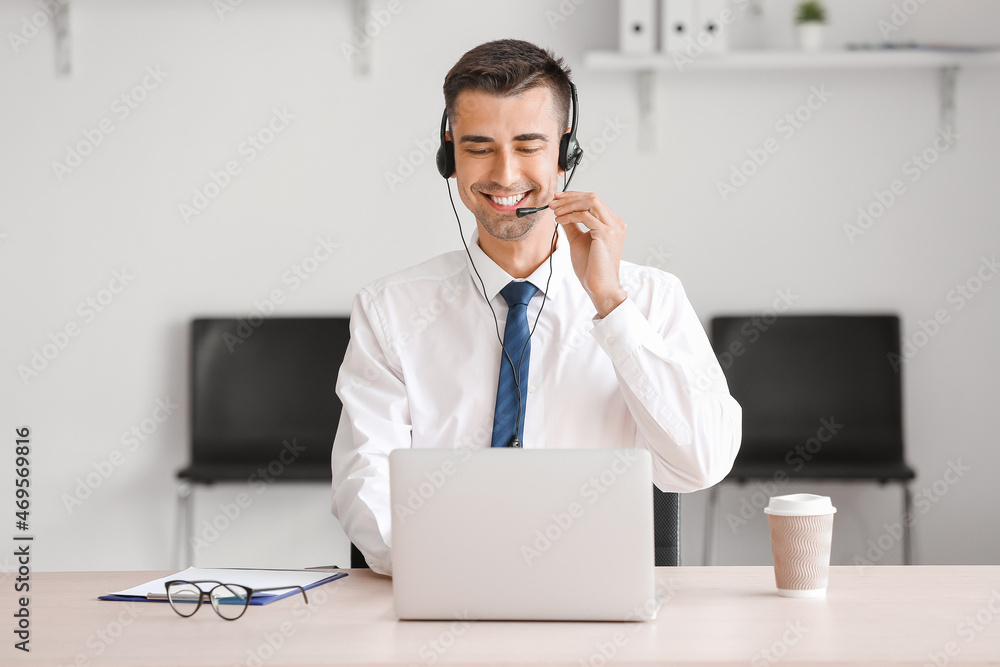 Male consultant of call center working with laptop in office