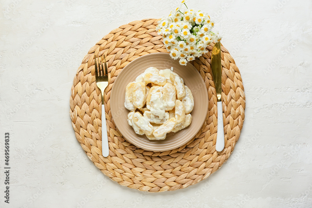 Delicious dumplings in plate and cutlery on light background