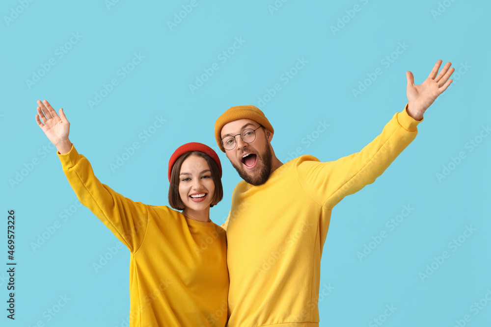 Happy young couple in stylish winter clothes on color background