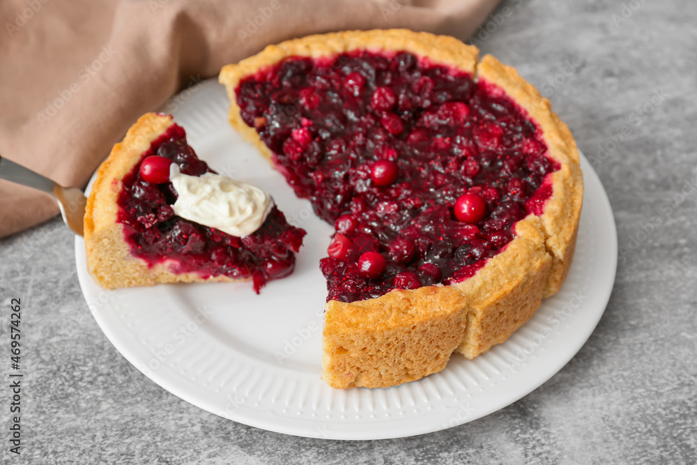 Plate with tasty lingonberry pie and dip on grey background