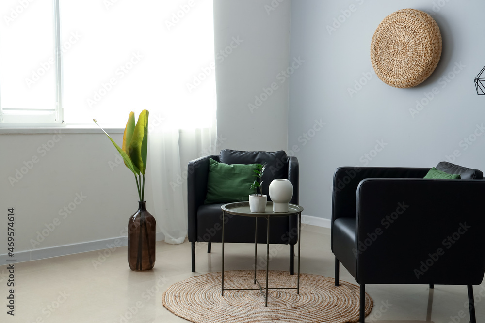 Interior of stylish living room with black armchairs and table