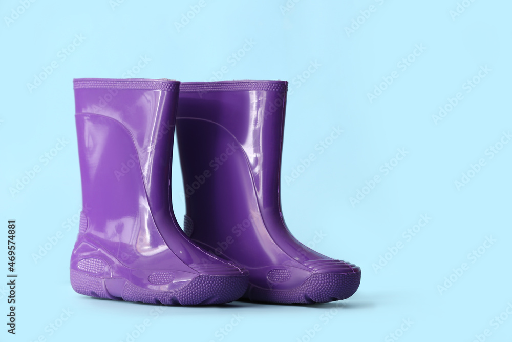 Rubber rain boots on color background