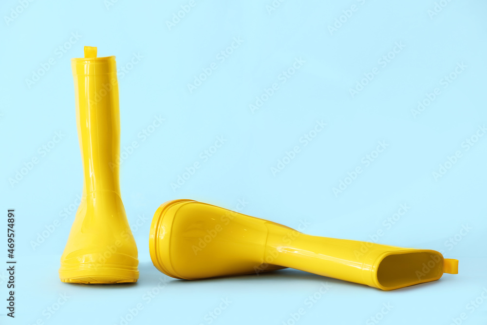 Pair of yellow rubber boots on color background