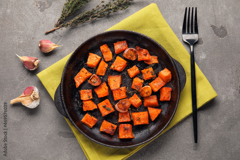 Frying pan with tasty roasted pumpkin pieces on grey background