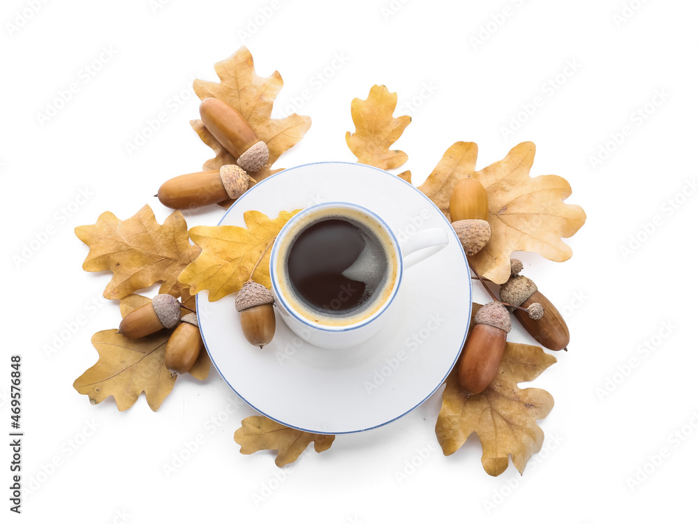 Cup of coffee with acorns and autumn leaves on white background