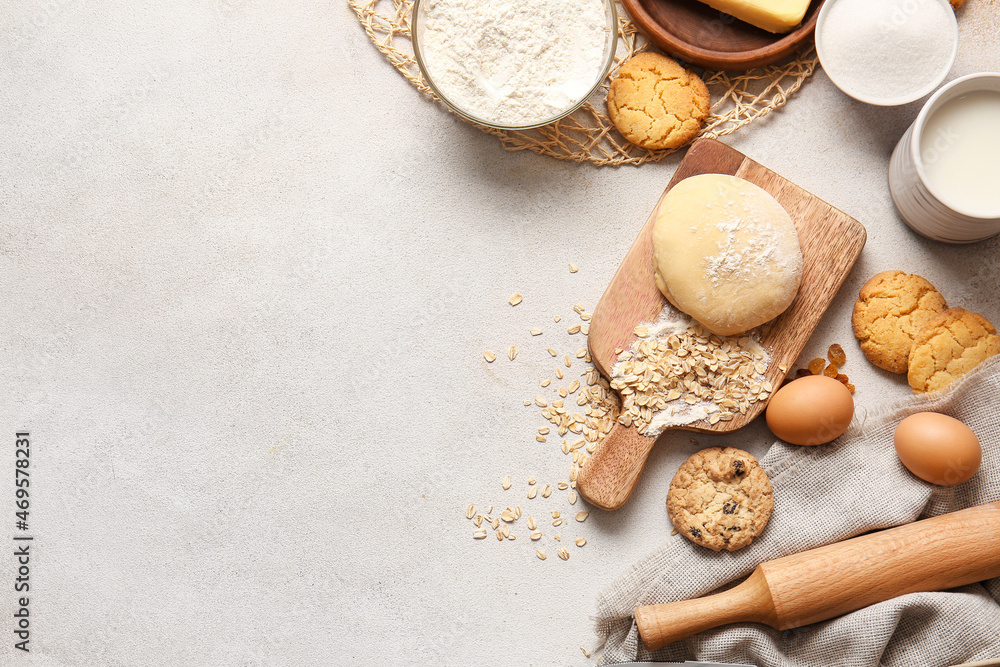 Wooden board with fresh dough and ingredients for preparing homemade cookies on light background