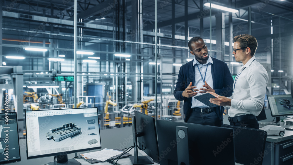 Two Diverse Automotive Industrial Engineers Talking About Vehicle Production while Standing in Offic