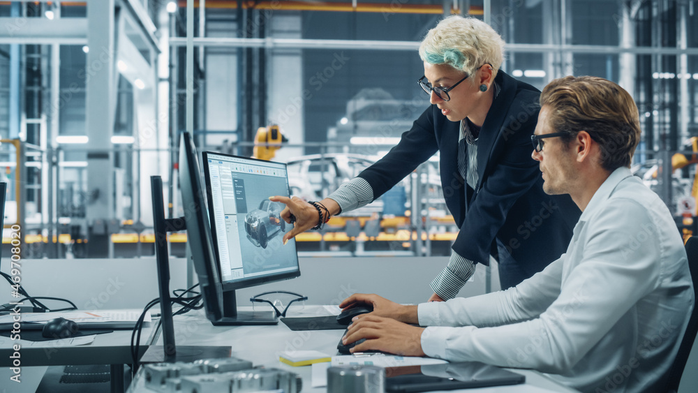 Two Automotive Engineers Discussing Concept Car Blueprints on Desktop Computer in Modern Office at A