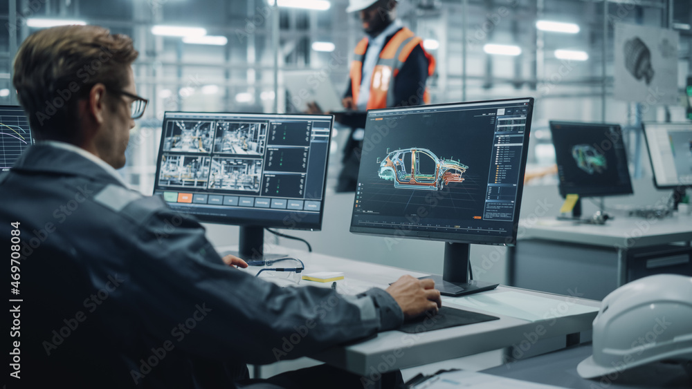 Vehicle Factory Line Operator Working at Desk, Overviewing Autonomous Electric Car Production. In th