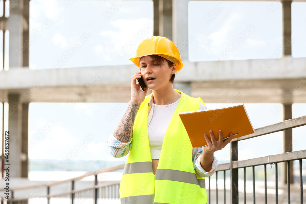 女建筑工人拿着文件夹在户外用手机聊天