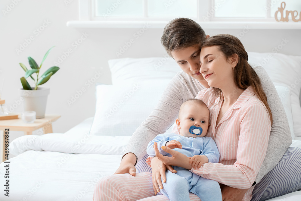 Young parents with little baby boy in bedroom