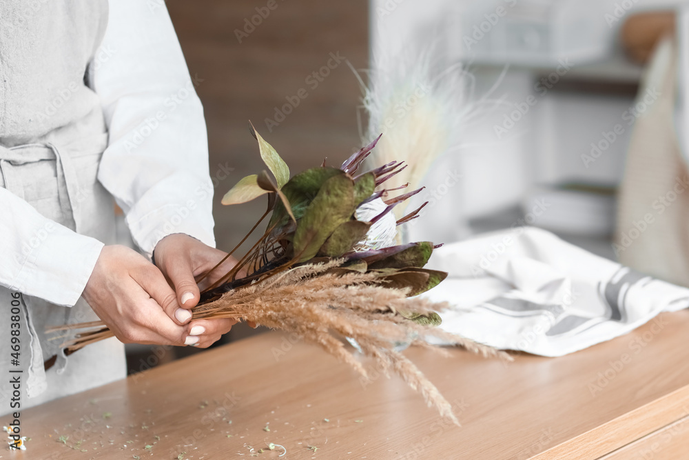 女花艺师在餐桌上用漂亮的干花制作花束，特写