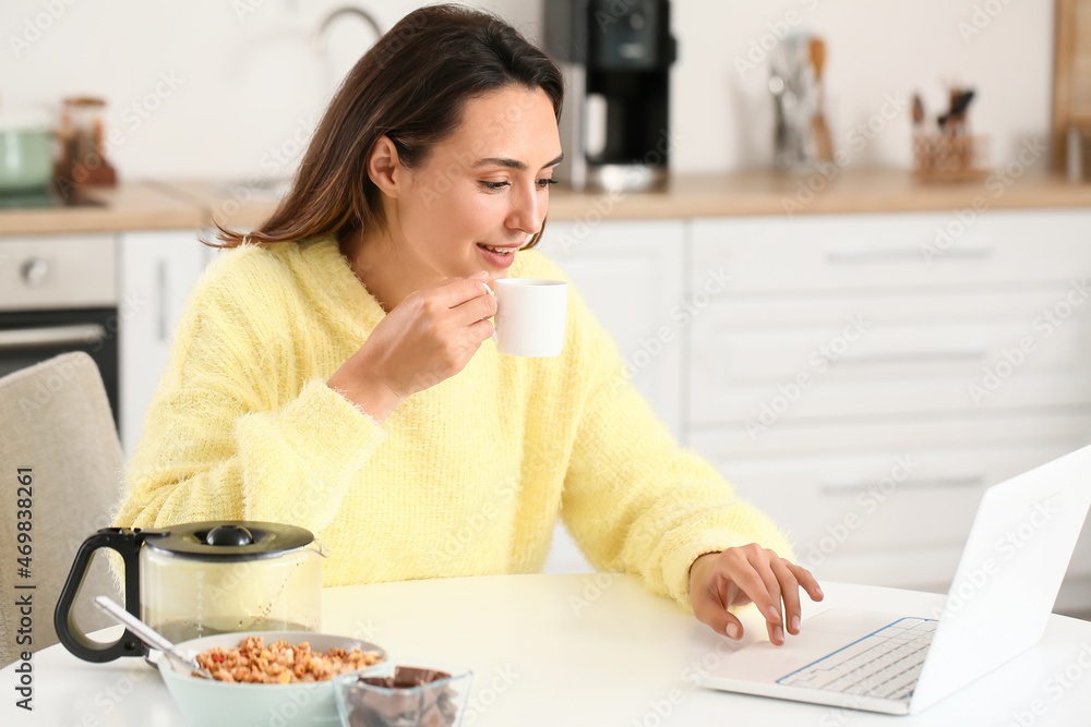 Morning of beautiful woman with laptop drinking coffee at home