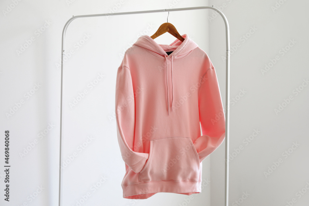 Rack with hoodie near light wall