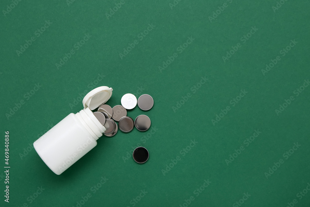 Plastic bottle with lithium button cell batteries on green background