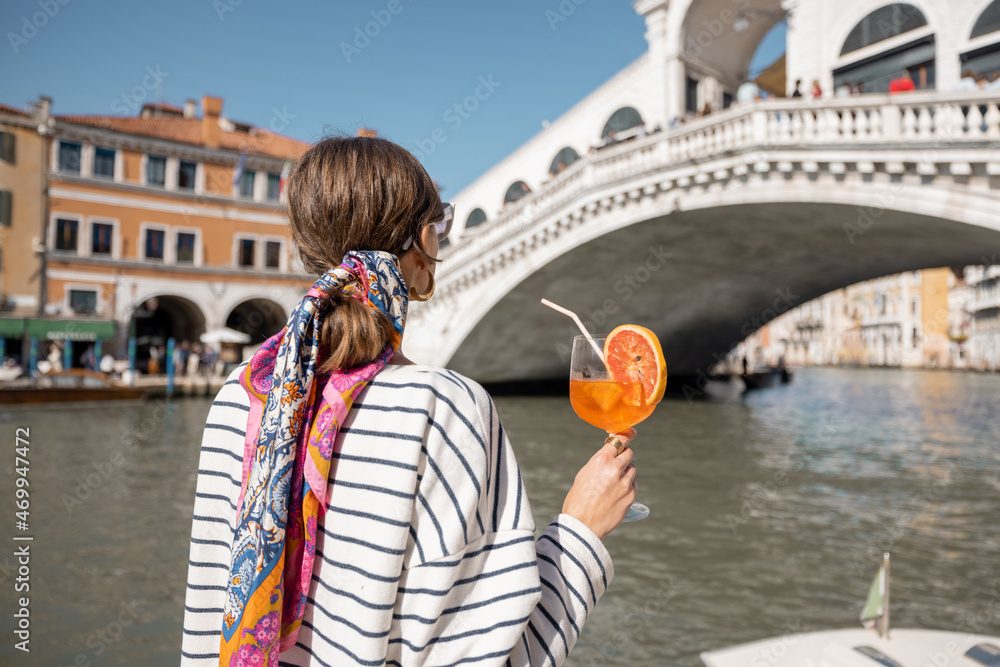 Young woman enjoying summer cocktail on the background of famous Rialto bridge in Venice. Concept of