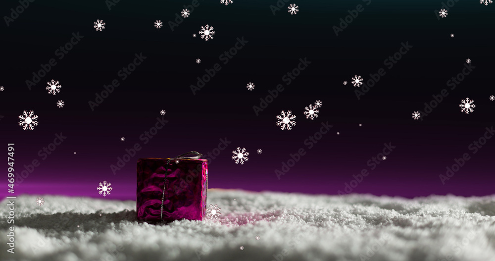 Image of snow falling over christmas present with pink light in a night sky