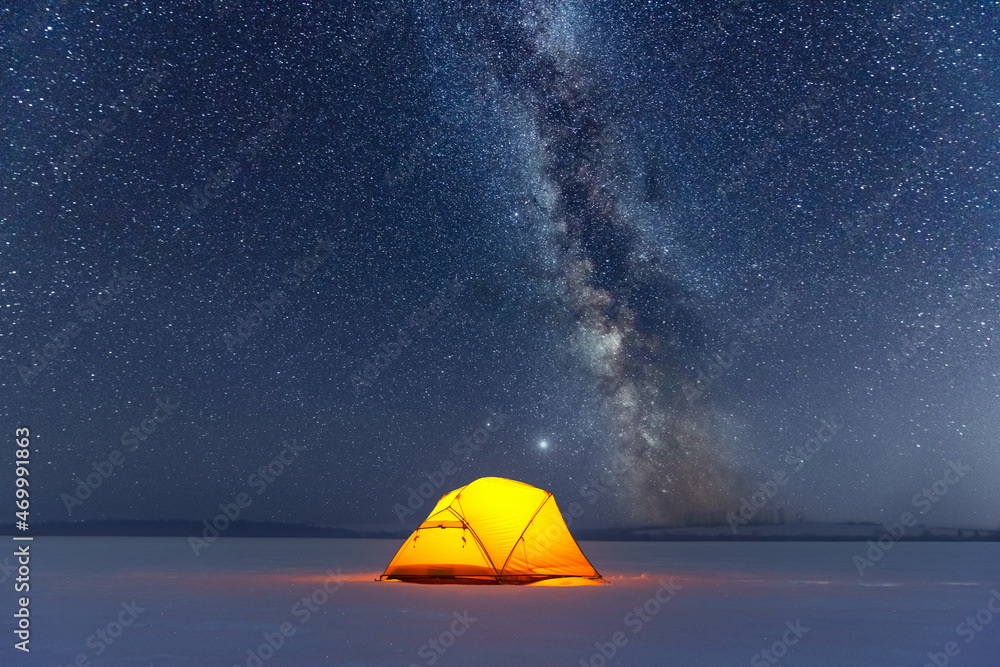 Yellow tent lighted from the inside against the backdrop of incredible starry sky with Milky way. Am