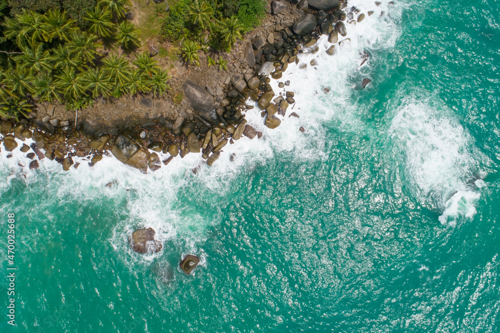 Aerial top view of sea waves crashing on rocks with coconut palm trees Beautiful seashore in Phuket 