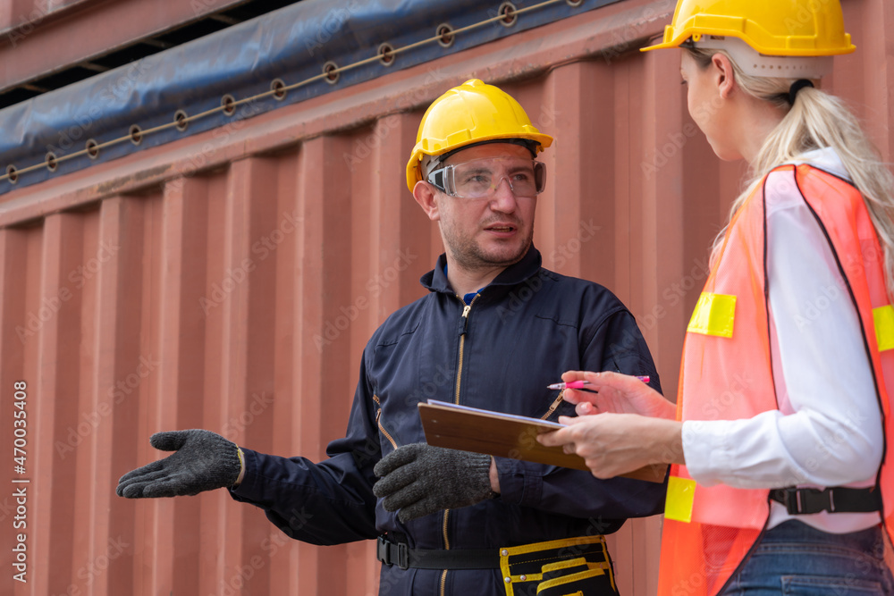 Industrial worker works with co-worker at overseas shipping container yard . Logistics supply chain 