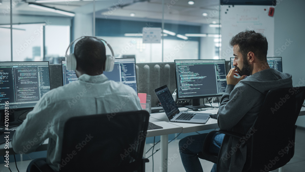 Office: Professional Black IT Programmer Uses Headphones while Working on Desktop Computer. Male Web