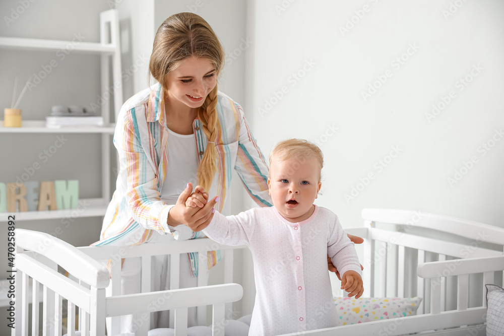 Young mother and her cute little baby in crib