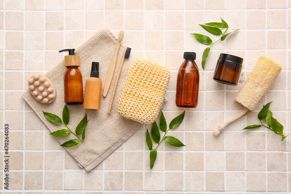 Set of bath supplies with sponges and plant branches on beige tiles