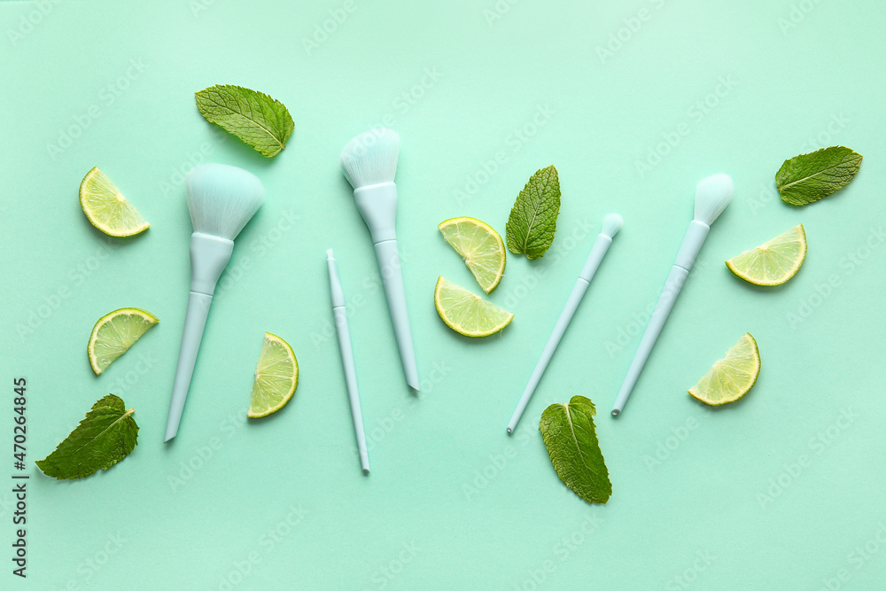 Stylish makeup brushes with lime and mint on color background