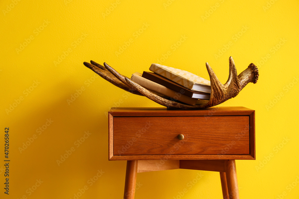 Wooden bedside table with decor near yellow wall