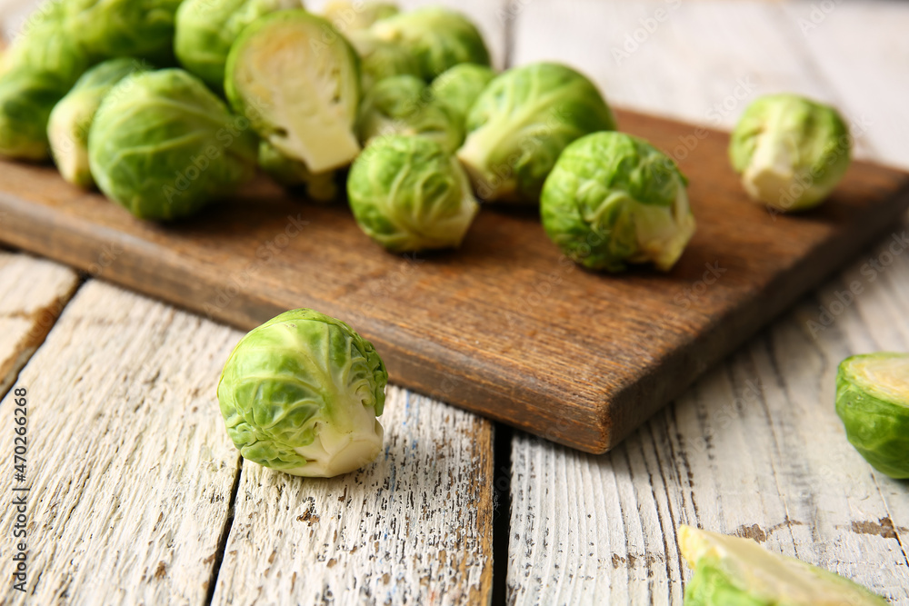 Board with fresh Brussels cabbage on light wooden background, closeup