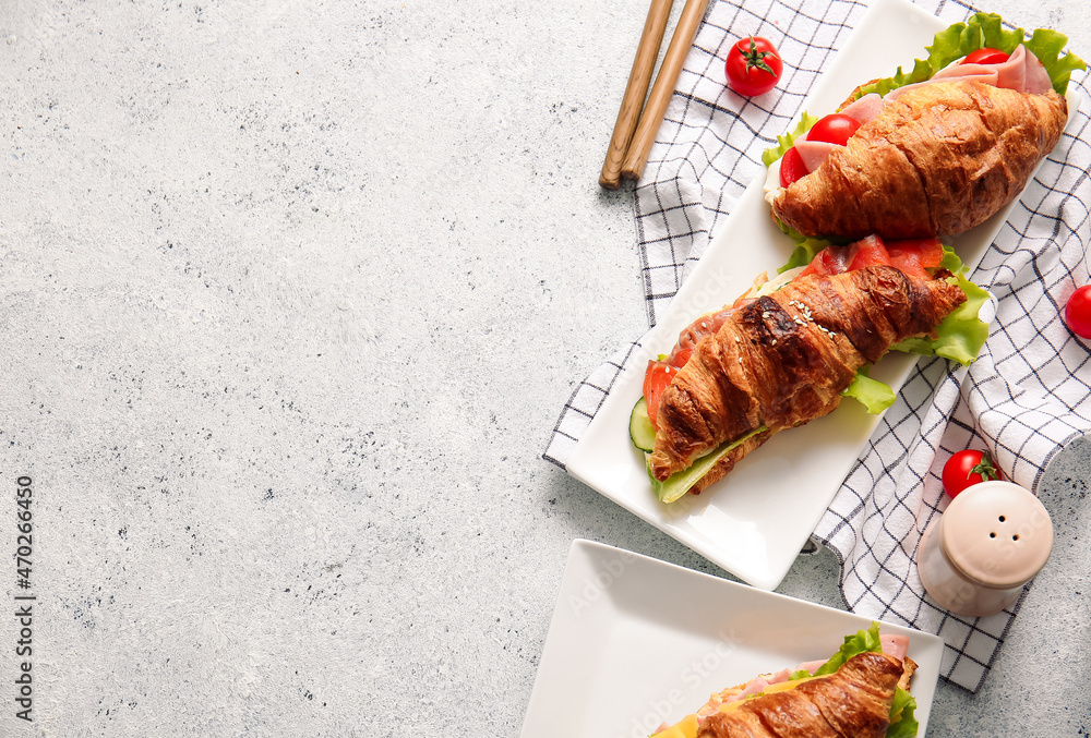 Plates with delicious croissant sandwiches on light background