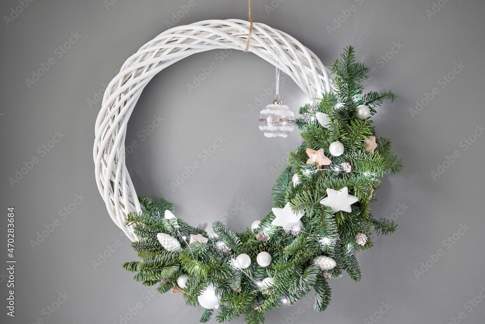 Beautiful festive wreath of fresh spruce on Gray wall. Xmas circlet with ornaments and balls. Christ