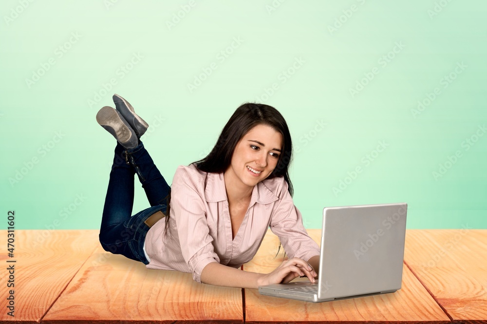 Beautiful young smiling woman in casual outfit sitting and working on her laptop.